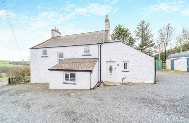 A large, detached farmhouse with open views of the countryside.