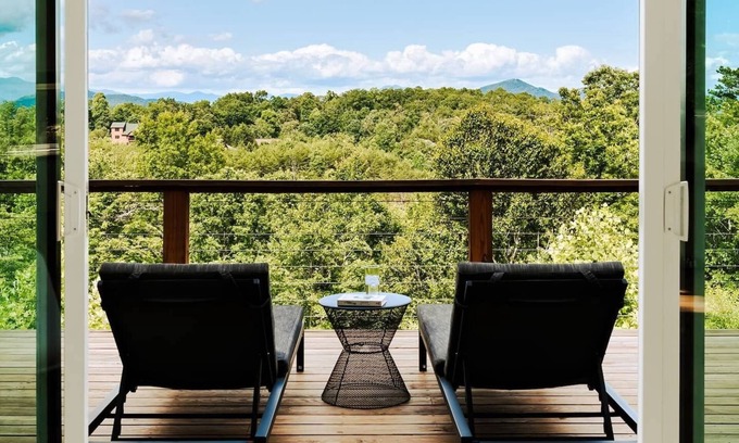 Young Harris Cabin | EcoModMtn is a 3BR/3.5BA luxury retreat with panoramic fall views, floor-to-ceiling windows, a gas fireplace, private hot tub, firepit, and designer kitchen. Perfect for families, couples, or friends seeking cozy mountain elegance this autumn.