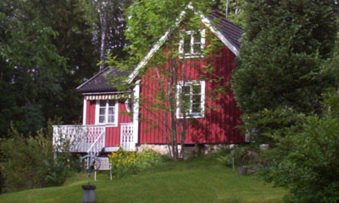 Vissefjaerda House | Red and white cottage with a boat not far from the lake